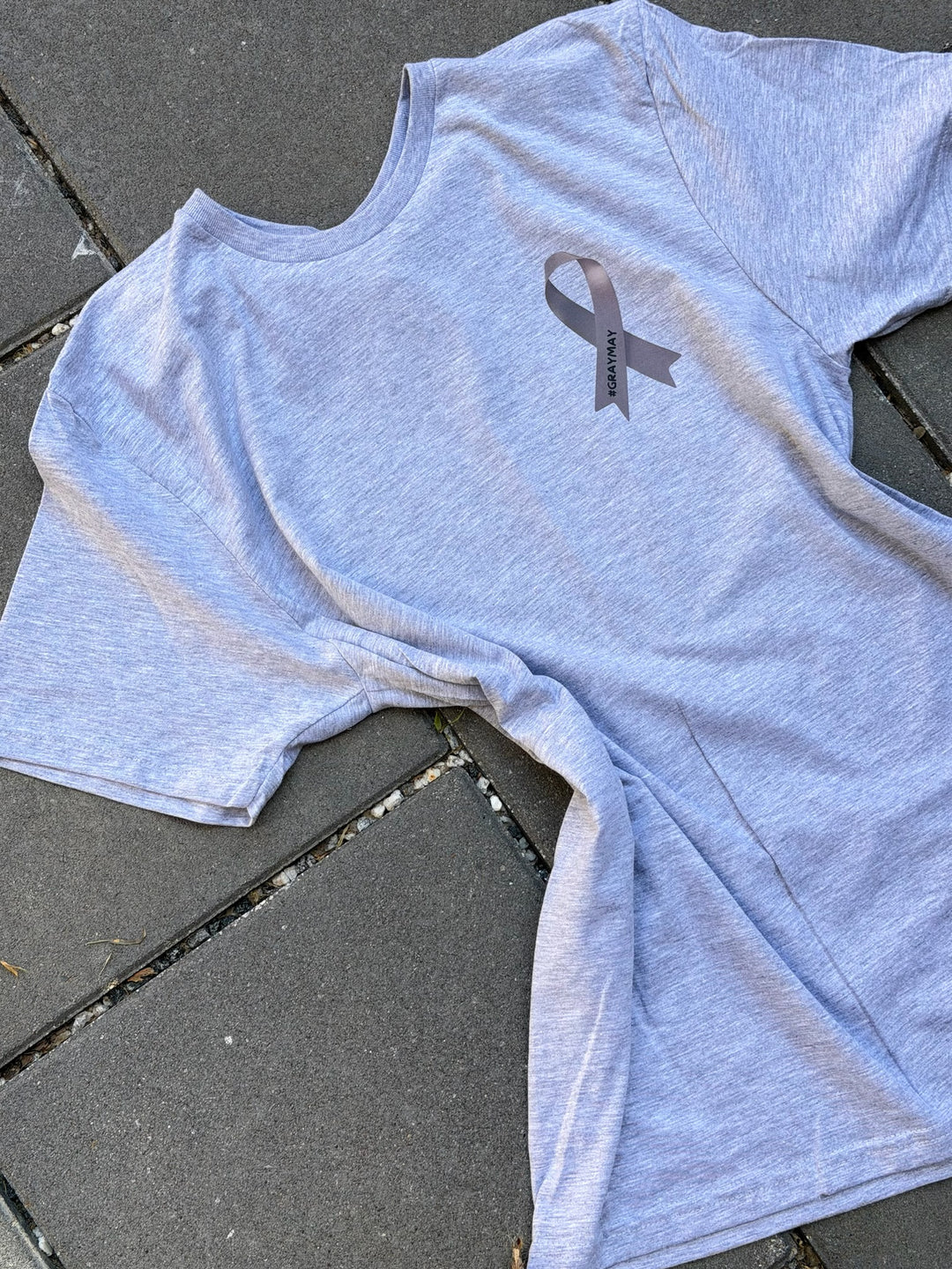 Gray t-shirt with a gray ribbon symbol on a dark surface