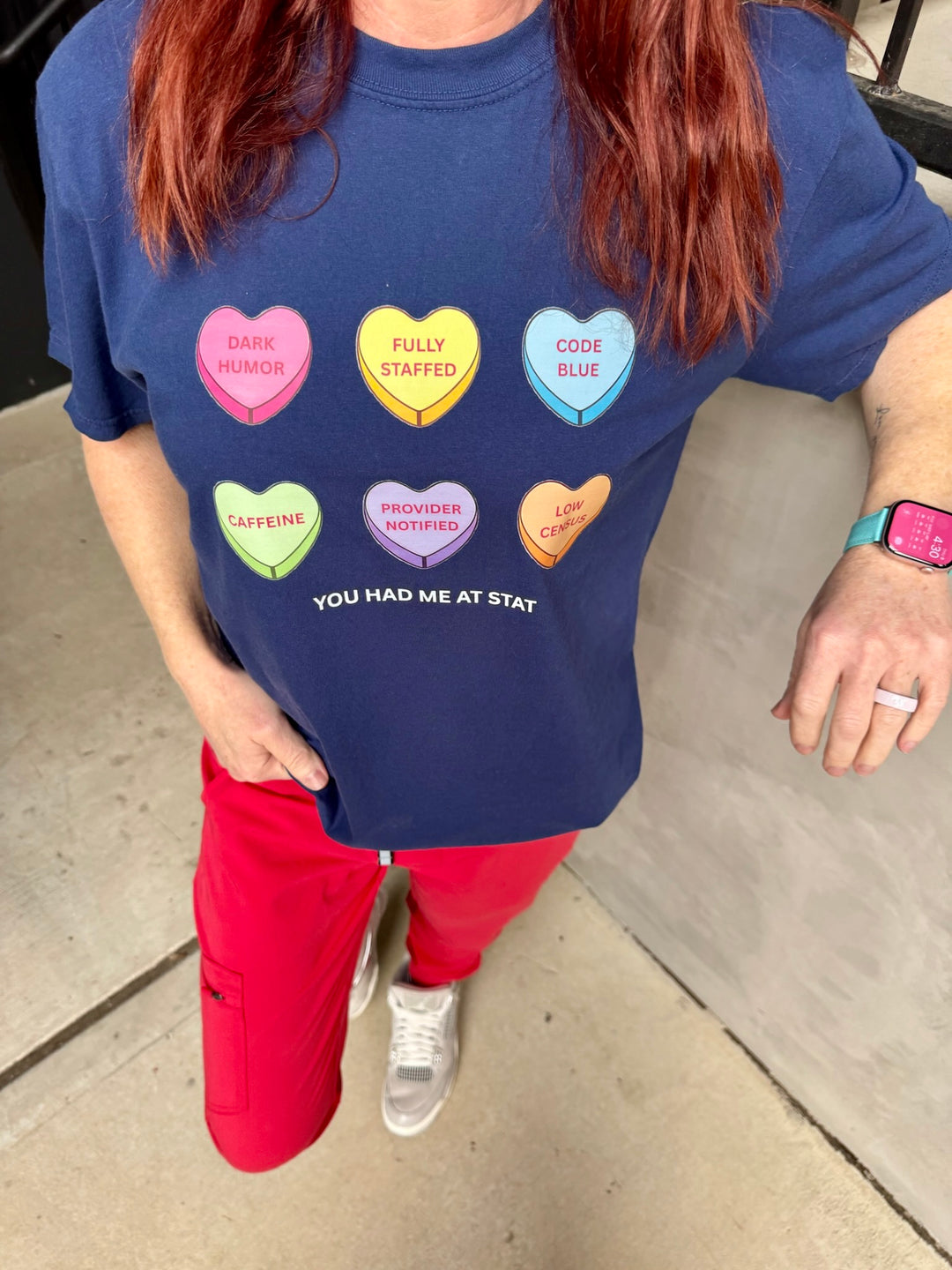 Person wearing a blue t-shirt with colorful heart-shaped candy designs and text.