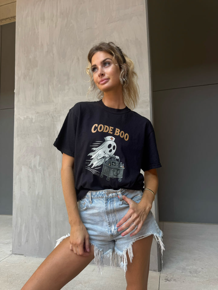 Model wearing the black Scrubhacks Collab: Code Boo Tee – Halloween Shirt for Healthcare Heroes. It shows a nurse ghost with a creepy code cart.