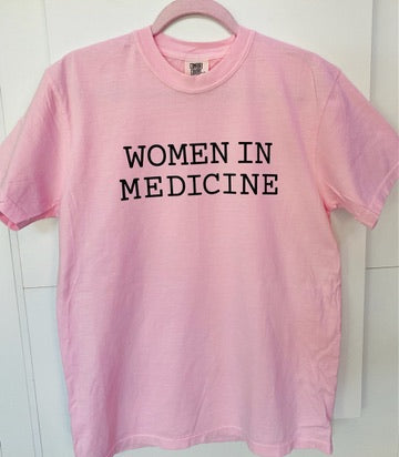 Pink t-shirt with 'WOMEN IN MEDICINE' text on a white background