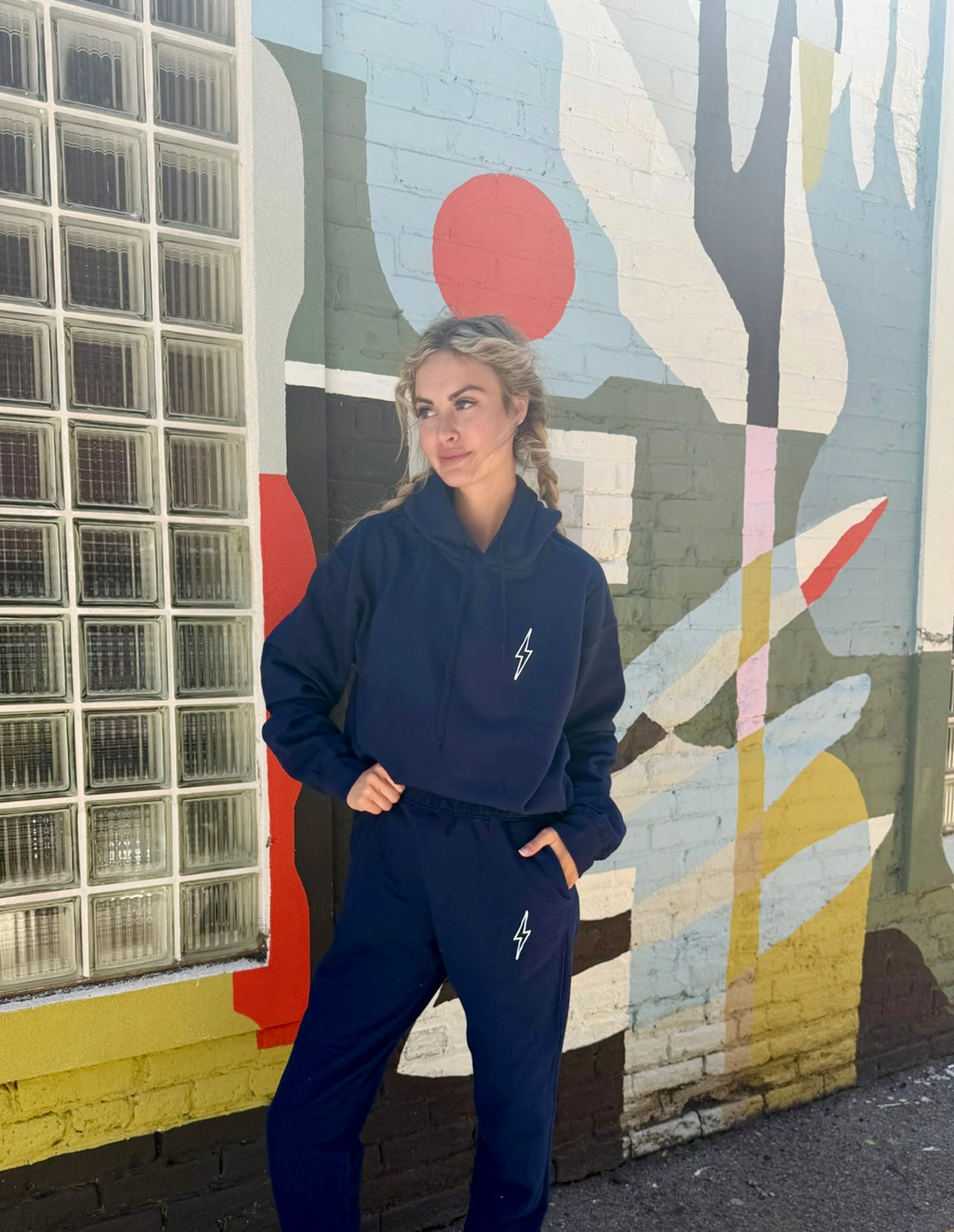 Person wearing a navy blue tracksuit standing in front of a colorful mural.