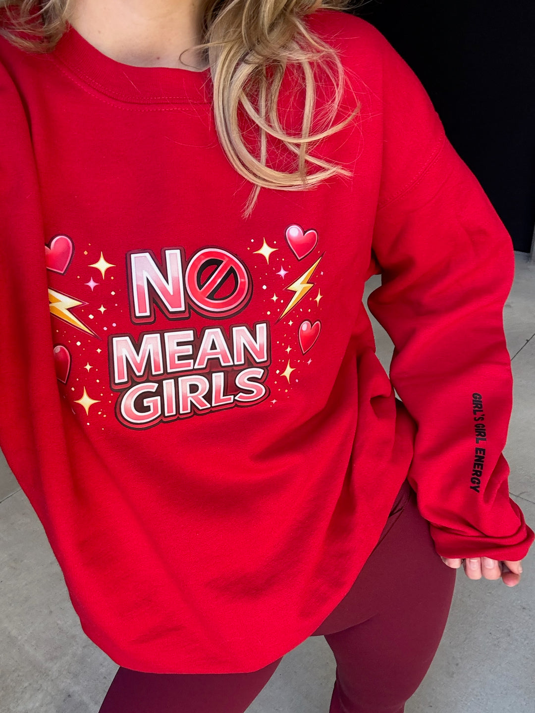 Red sweatshirt with 'No Mean Girls' text and graphics worn by a person.