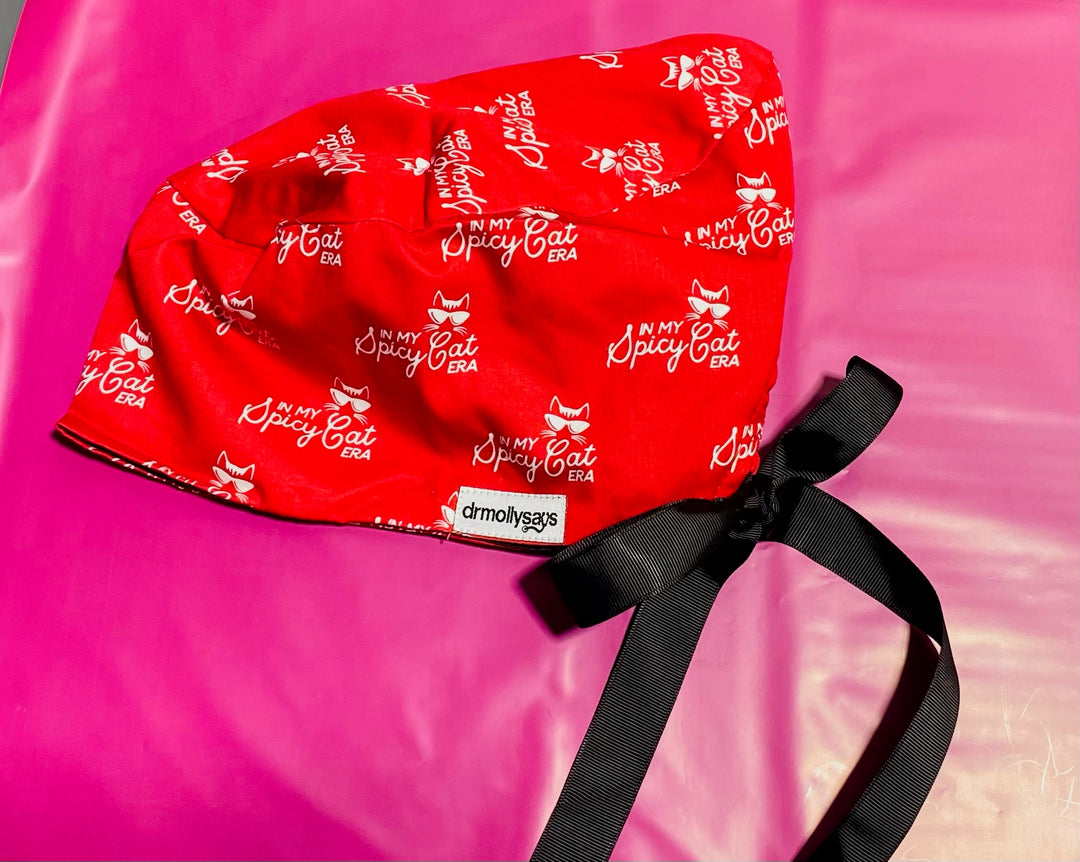 Red scrub hat with 'In My Spicy Cat' text on a pink background