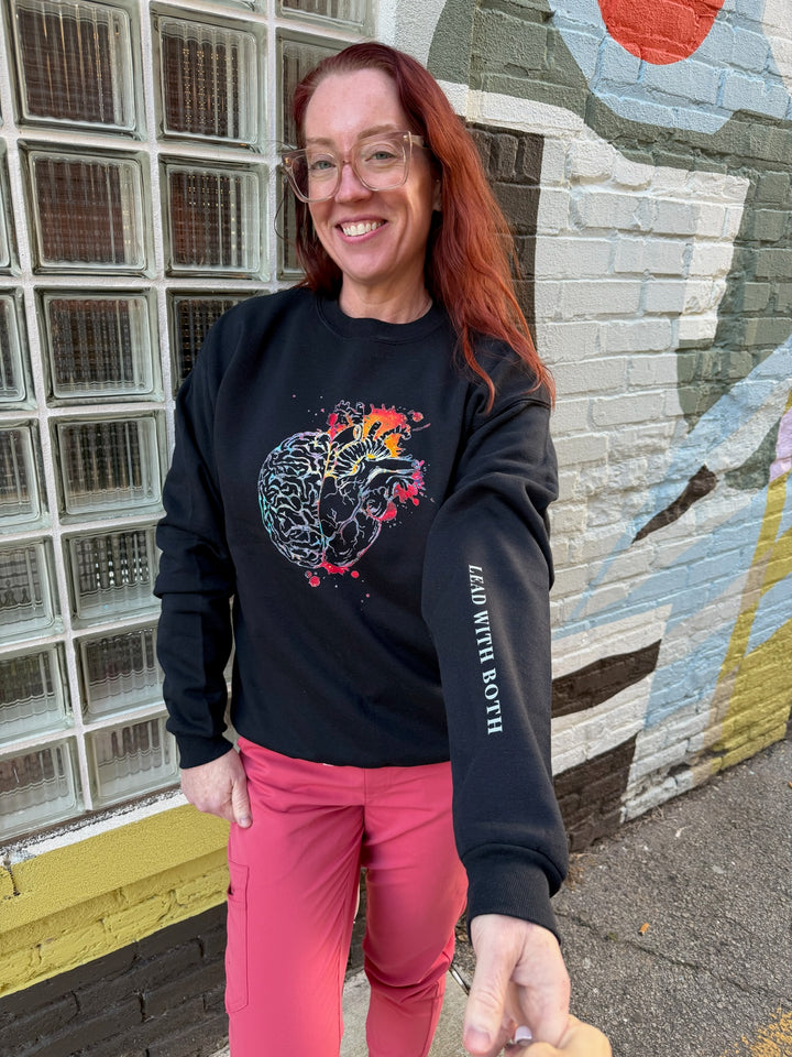 Black Synapse and Soul Anatomical Brain Heart Sweatshirt worn by Dr. Betsy Grunch, showing the sleeve motto "Lead with both"