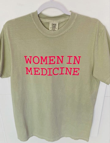Green t-shirt with 'WOMEN IN MEDICINE' in pink text on a white background