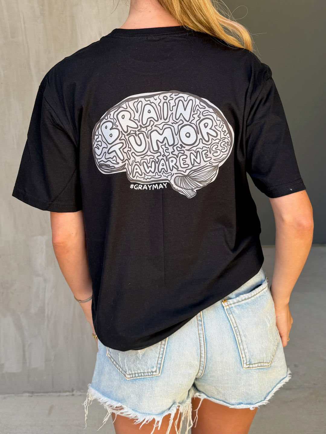 Person wearing a black t-shirt with a brain tumor awareness design on the back.