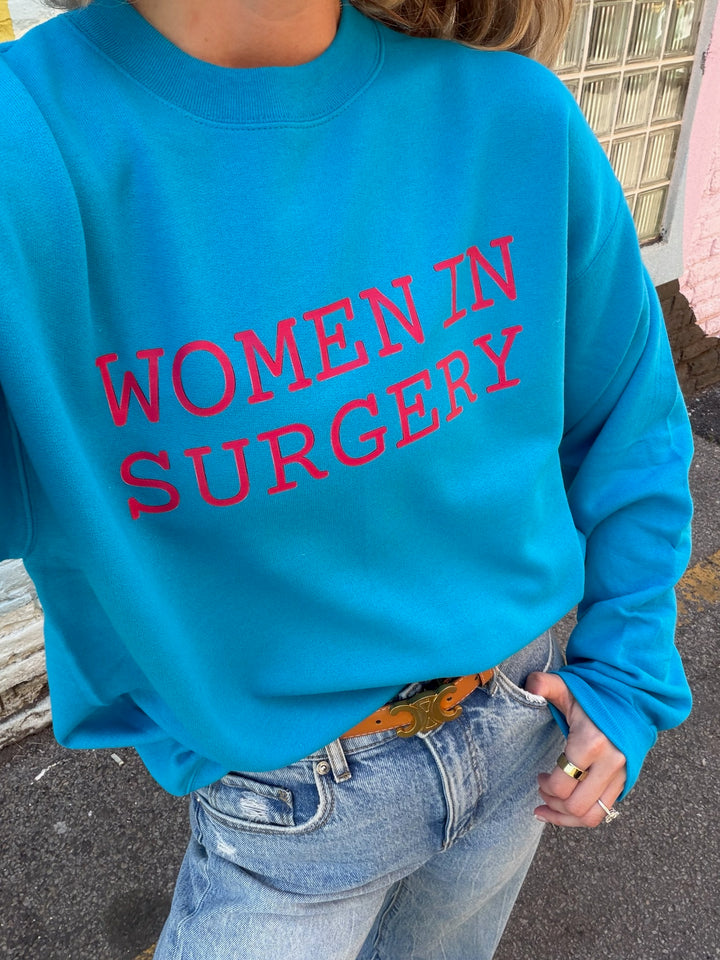 Person wearing a blue sweatshirt with 'WOMEN IN SURGERY' text.
