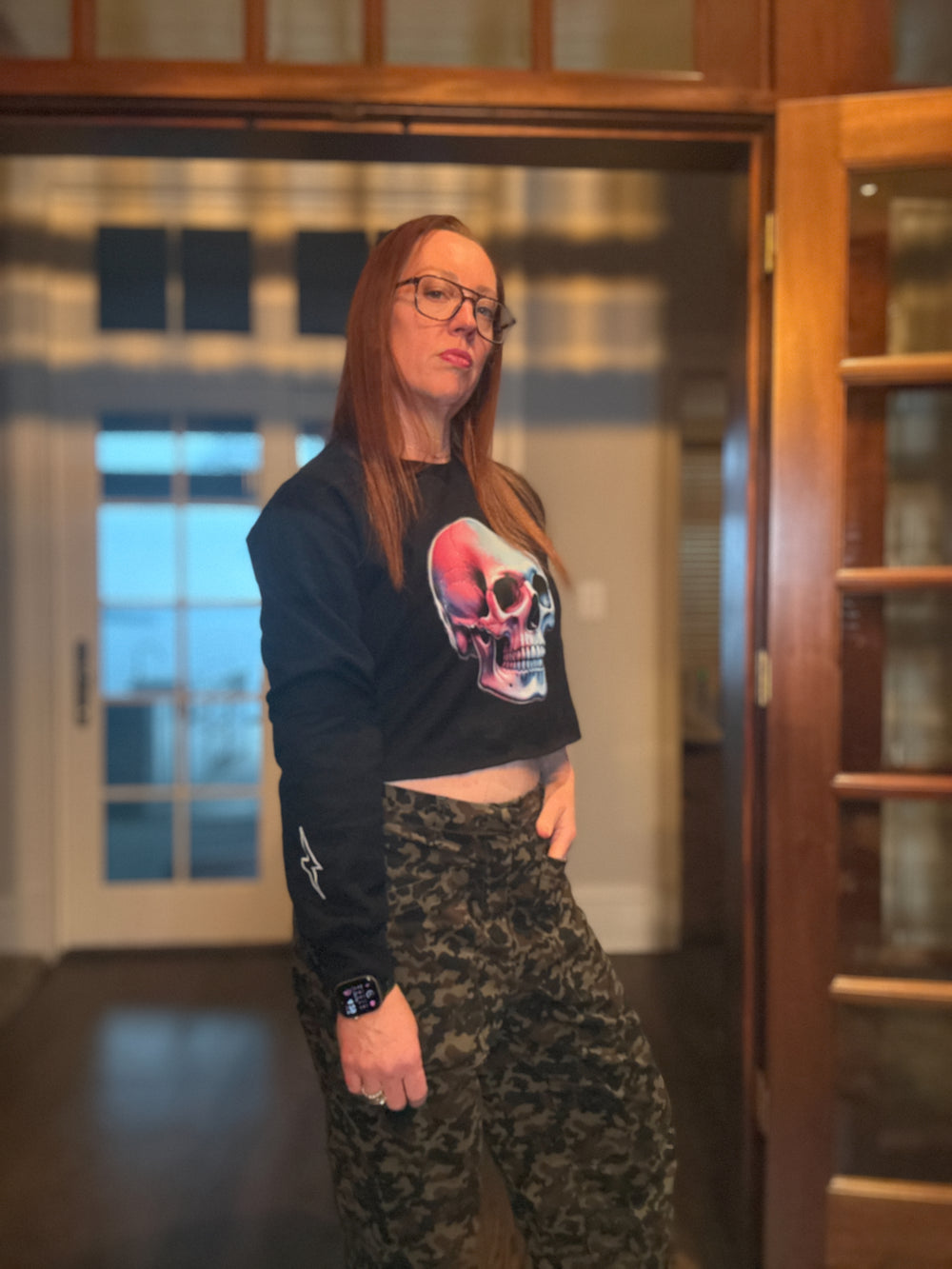 Dr. Betsy Grunch wearing the Super Skull Cropped Crewneck Sweatshirt - Black Crop Top Shirt with Skull Design and showing off her signature lightning bolt on the sleeve.