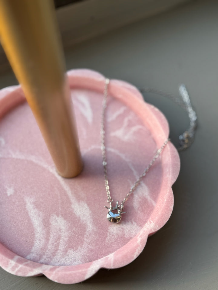 Silver Lumbar Spine Vertebra Necklace in a pink scalloped tray