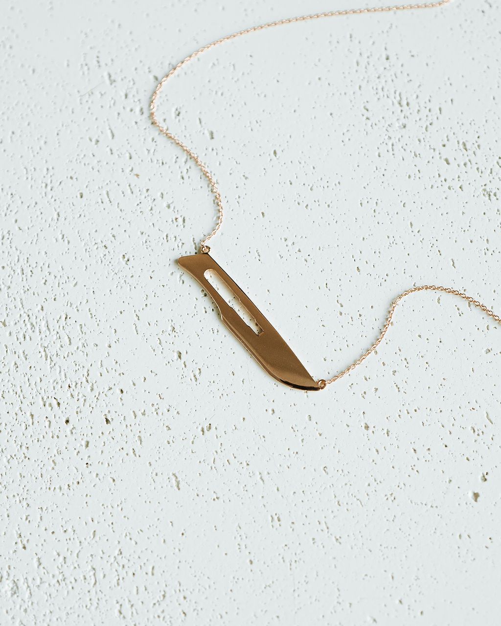 Flat lay of rose gold 10 Blade Scalpel Pendant Necklace