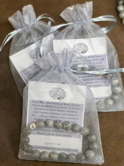 Glioblastoma awareness bracelets packaged in gray organza gift bags with informational cards about brain tumor awareness.