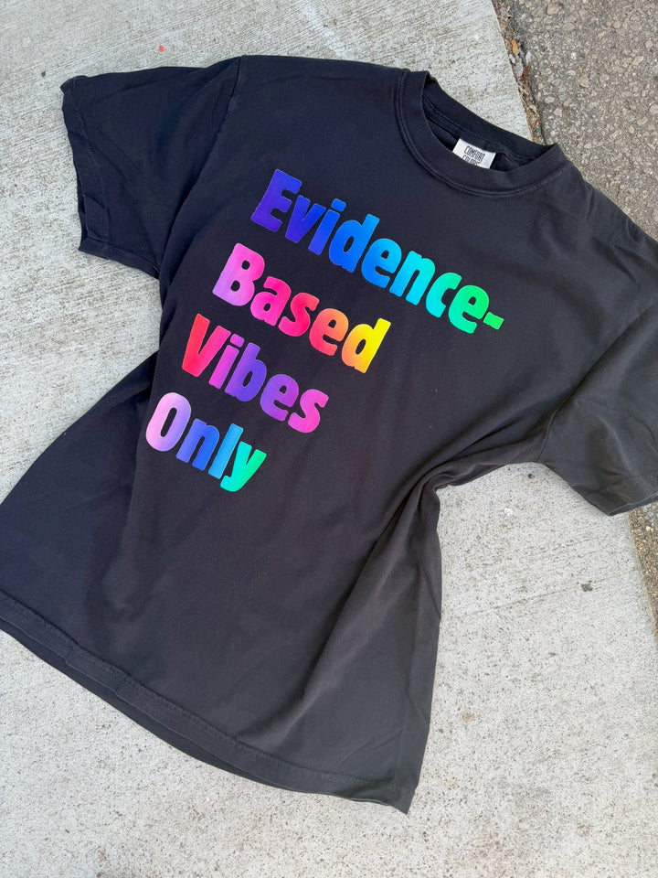Black t-shirt with colorful text 'Evidence-Based Vibes Only' on a concrete surface