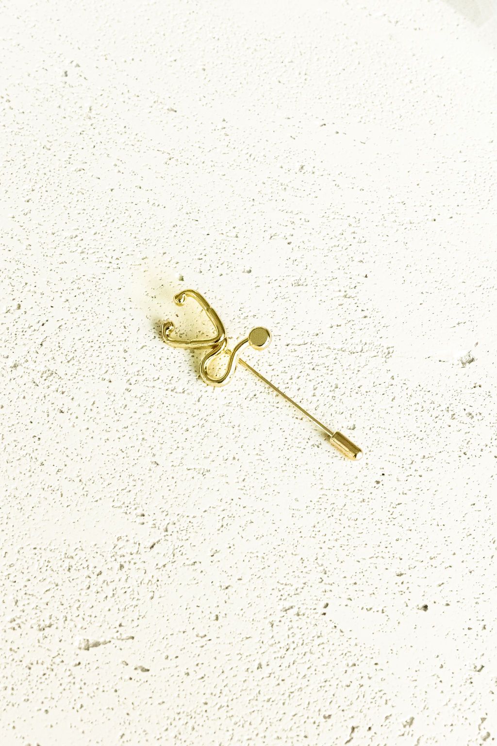 Gold Stethoscope Jacket Lapel Pin on a white surface