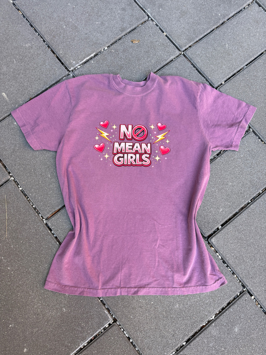 Purple t-shirt with 'No Mean Girls' text on a tiled floor