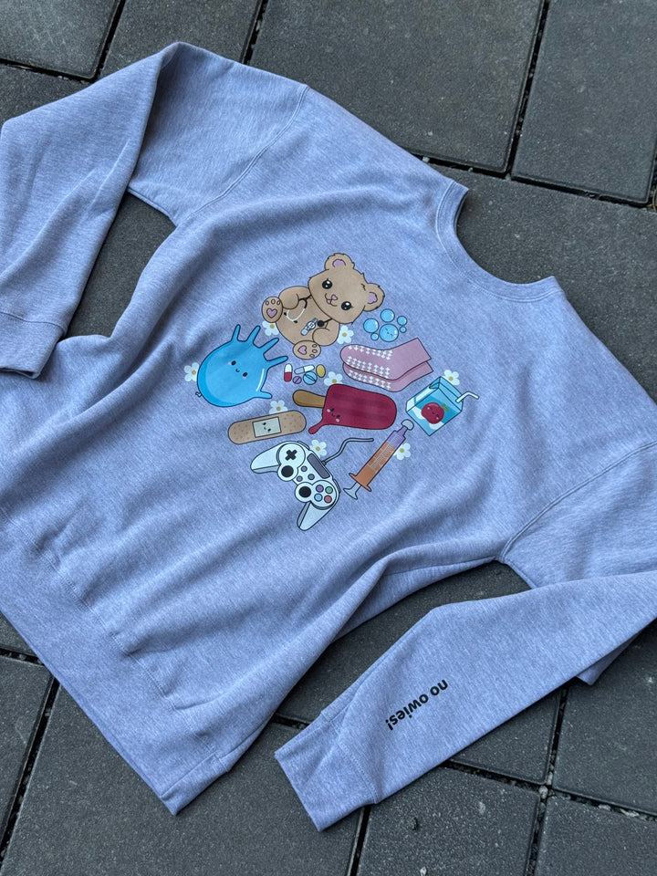 Flat lay of Ladyspinedoc X Scrubhacks No Owies! Pediatrics Collage Crewneck Sweatshirt - Heather Gray With Pedi Nurse Essentials with “No Owies!” on Sleeve