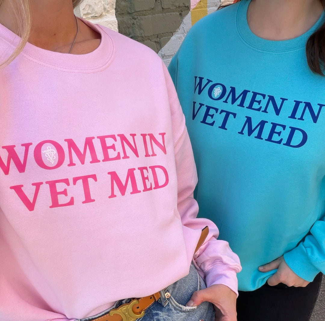 Two people wearing sweatshirts with 'WOMEN IN VET MED' text, one in pink and the other in blue.