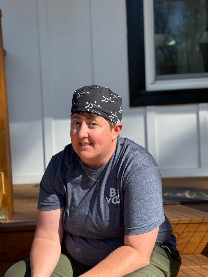 Left center view of Dr. Beachgem wearing the Ladyspinedoc x Dr. Beachgem Code Cart Cap - Black Scrub Hat with White Epinephrine (Adrenaline) Molecule Design