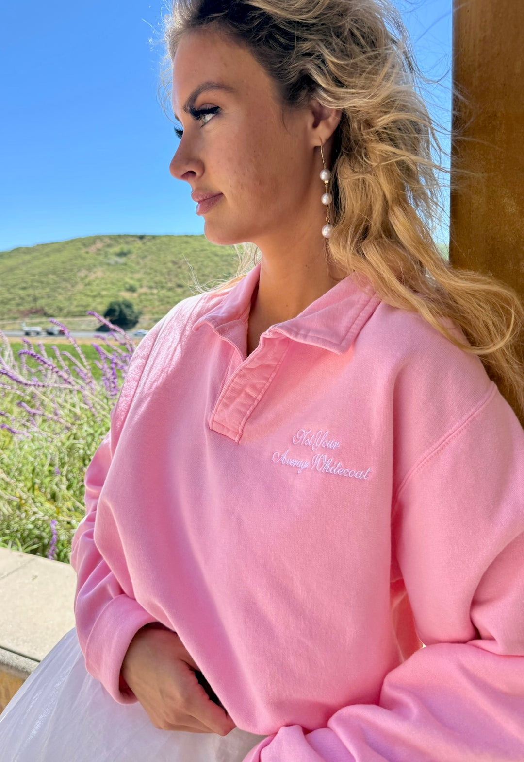 Woman wearing the Not Your Average Whitecoat Pink Polo Collar Sweatshirt, standing outdoors with a scenic background.