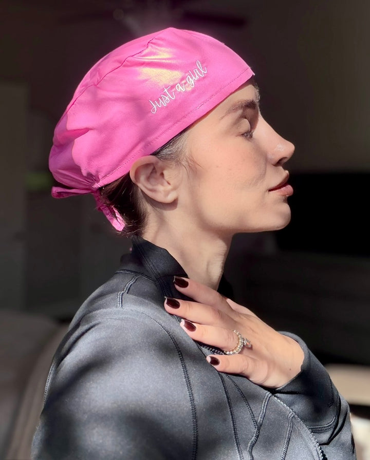 Dr. Daisy wearing a pink Just a girl scrub cap, looking to the side.