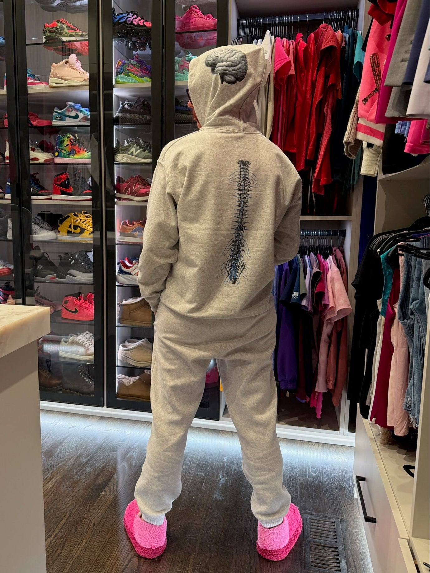 Ladyspinedoc in her cerebrospinal hoodie with pink shoes standing in front of a walk-in closet filled with shoes and clothing.