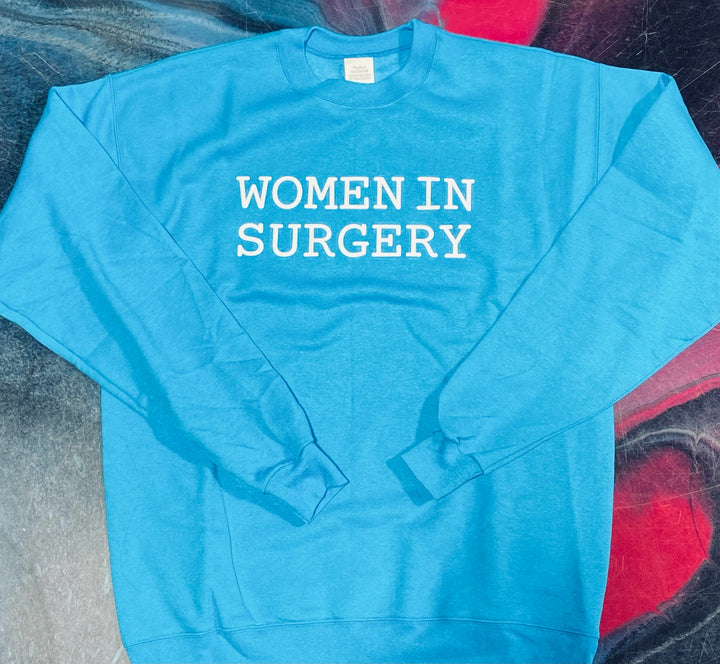 Blue sweatshirt with 'WOMEN IN SURGERY' text on a textured surface
