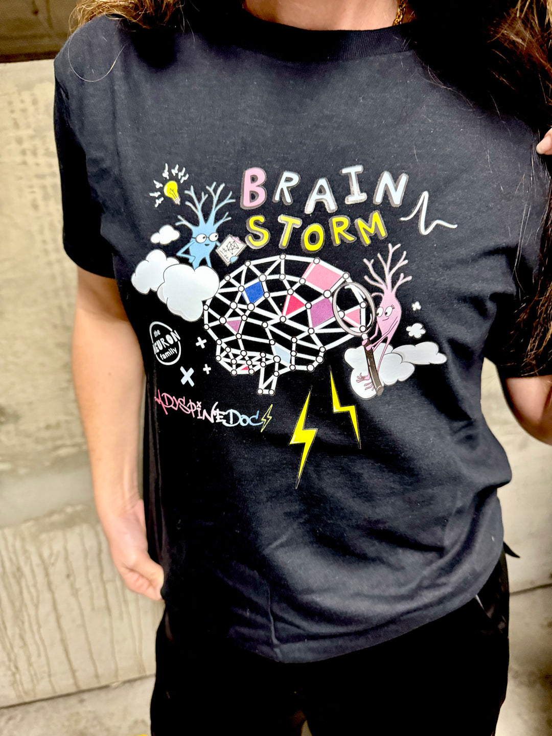 Close up view of the Ladyspinedoc x The Neuron Family brain storm / brainstorm tee shirt in black. 