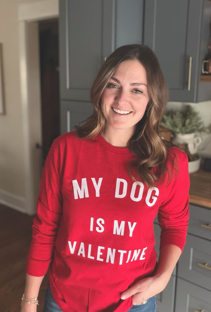 Dr. Molly wearing a red long-sleeve shirt with 'My dog is my valentine' text in a kitchen." 