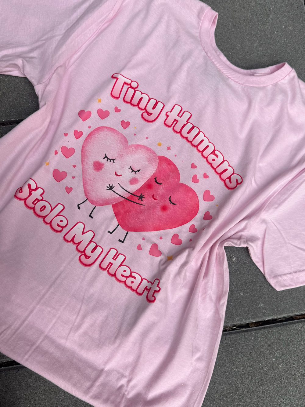 Flat lay of Pink Tiny Humans Stole My Heart Tee – Pediatric Valentine Shirt on a gray surface