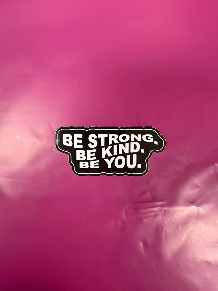Motivational sticker with 'Be Strong. Be Kind. Be You.' text on a pink background