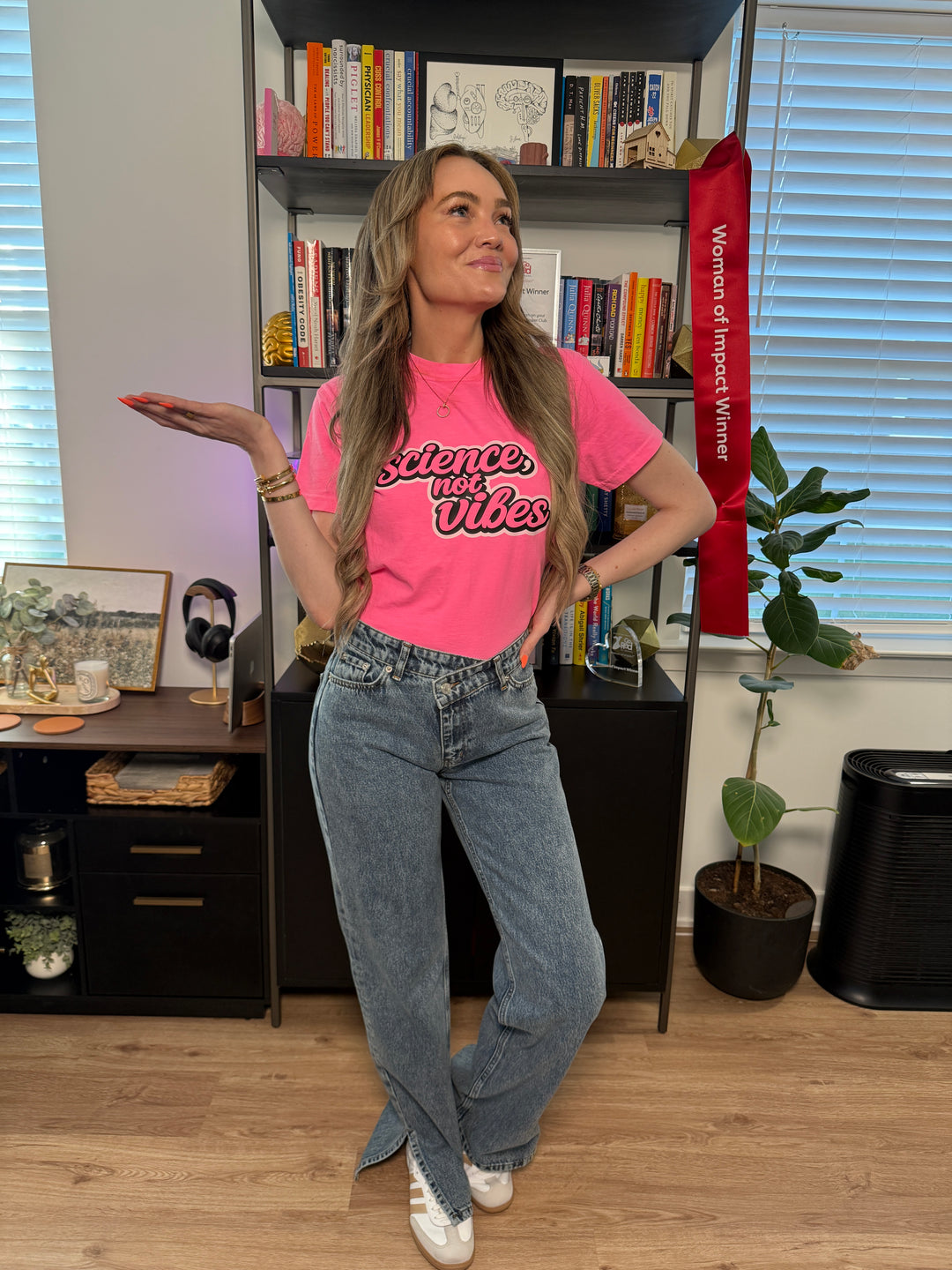 woman wearing hot pink shirt with "science, not vibes" on it; in an office