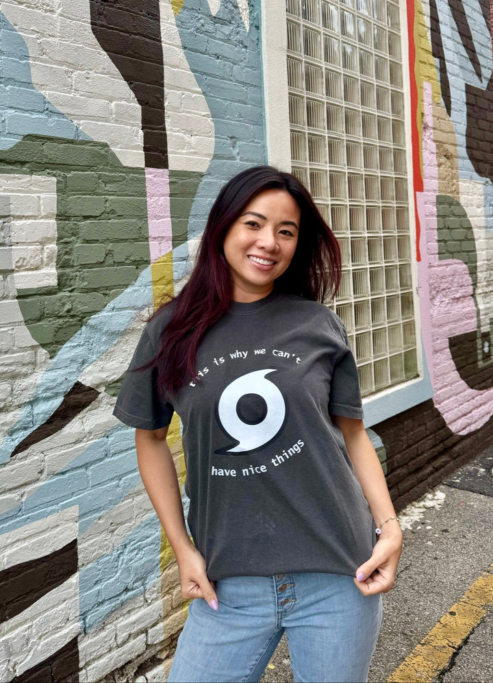 Woman wearing a t-shirt with a hurricane graphic design in front of a colorful mural.