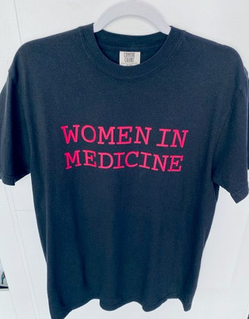 Black t-shirt with 'WOMEN IN MEDICINE' text in pink on a white background