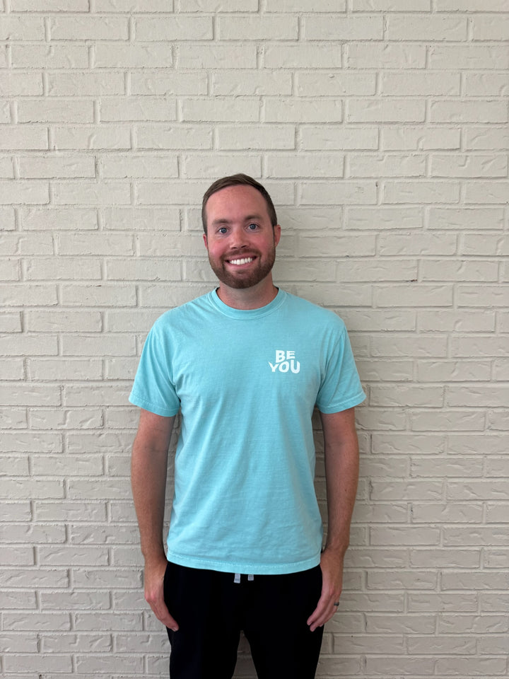 Male model wearing the BE YOU Tee Shirt in teal.