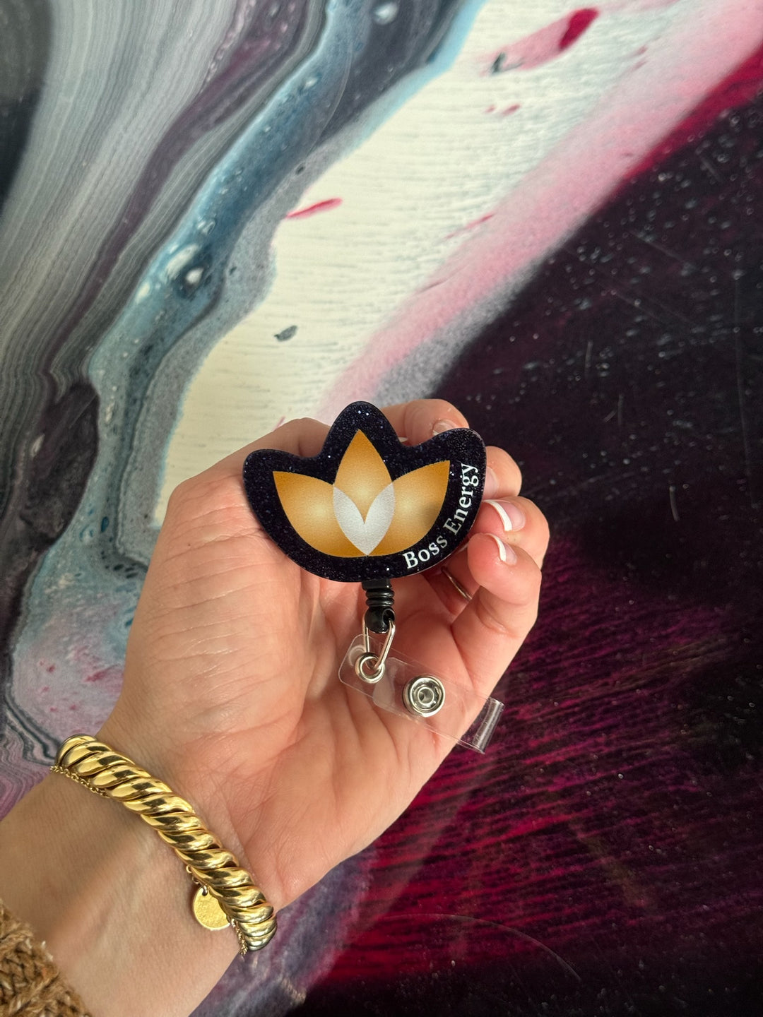 Hand holding a Boss Energy badge holder against a colorful abstract background