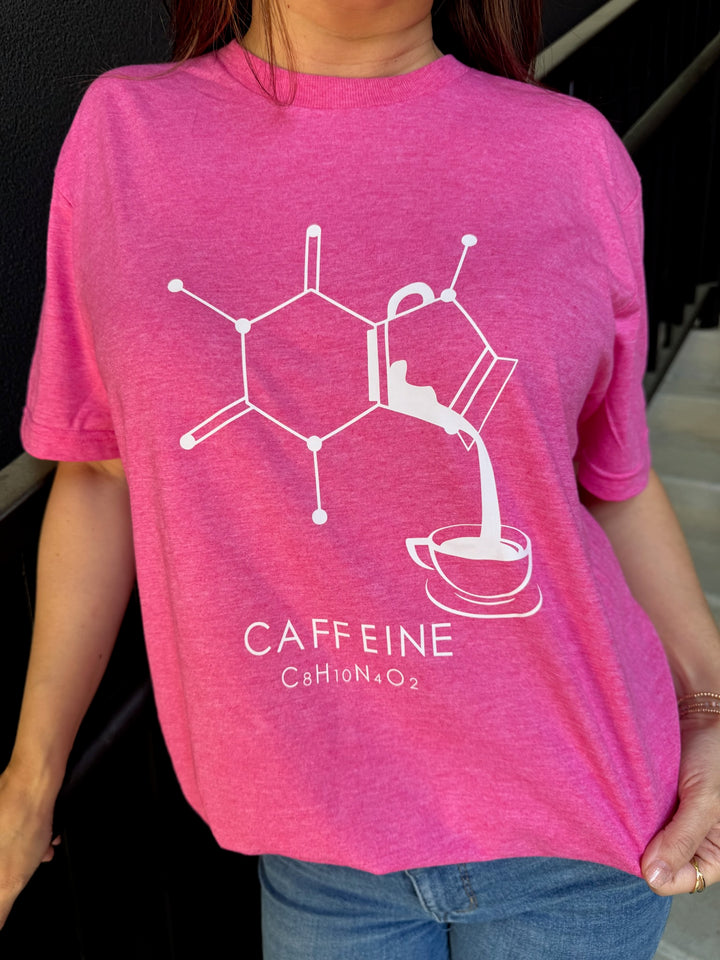 Person wearing a pink t-shirt with a white molecular design and 'CAFFEINE' text.
