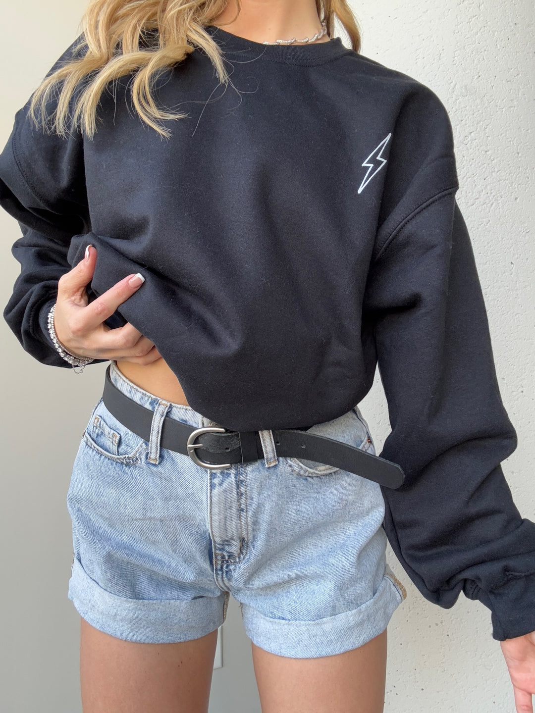 Model wearing The Incredible Sweatshirt, showcasing front lightning bolt detail and holding up the bottom hem on one side. 