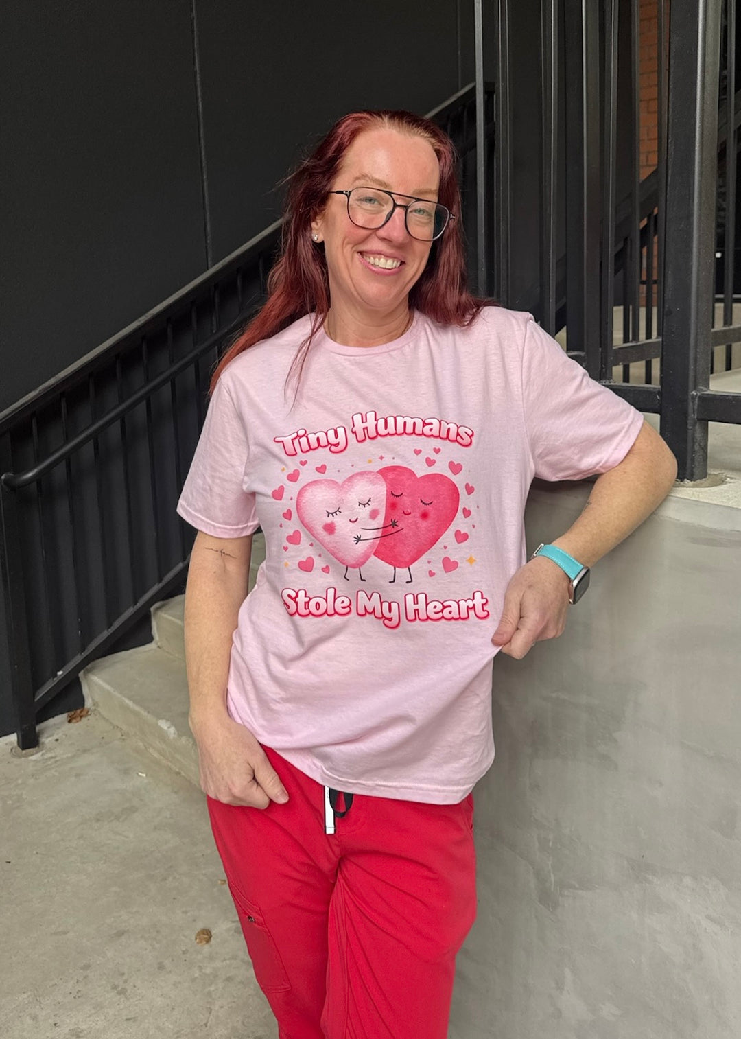 Ladyspinedoc wearing a pink Tiny Humans Stole My Heart Tee – Pediatric Valentine Shirt, standing outdoors.
