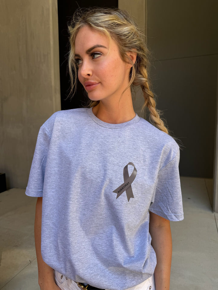 Woman wearing a light gray t-shirt with a #GRAYMAY gray ribbon symbol.