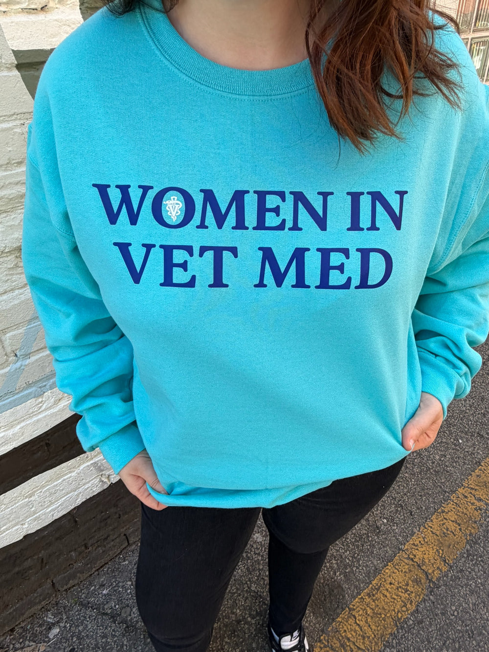 Woman wearing teal sweatshirt with 'Women in Vet Med' on the front