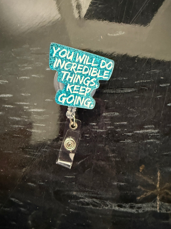Blue glitter "You Will Do Incredible Things. Keep Going." motivational quote badge holder on a dark background