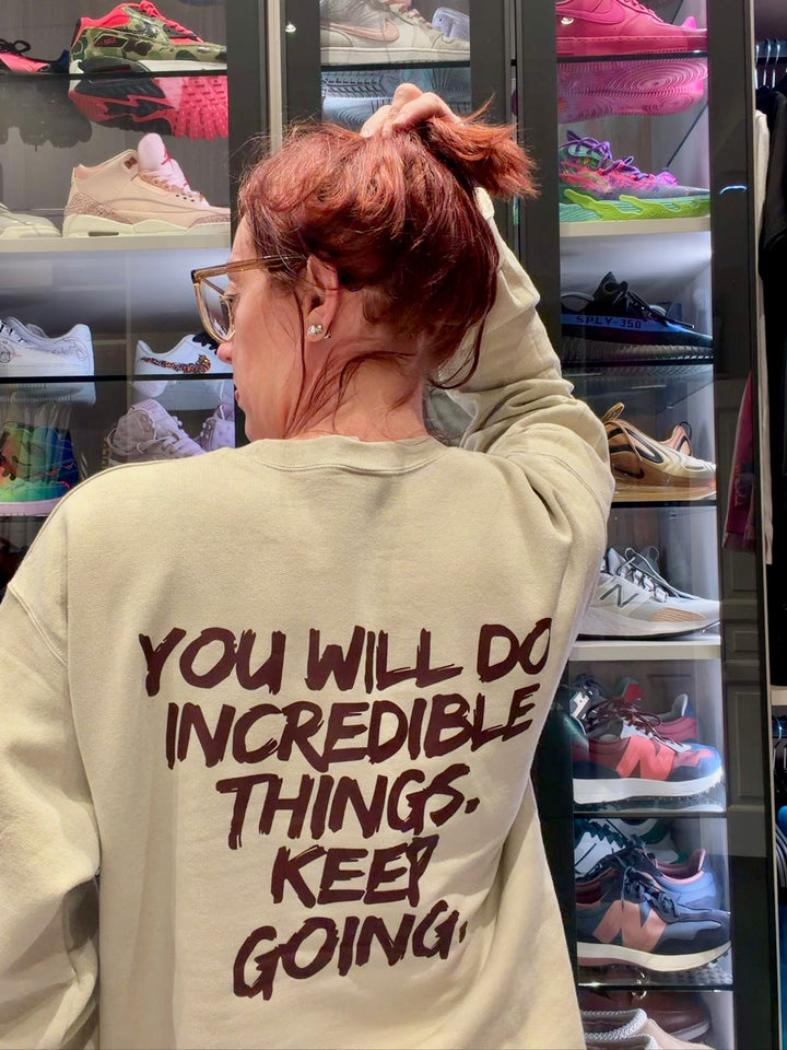 Ladyspinedoc wearing a sand-colored sweatshirt with motivational You Will Do Incredible Things. Keep Going. in her closet.