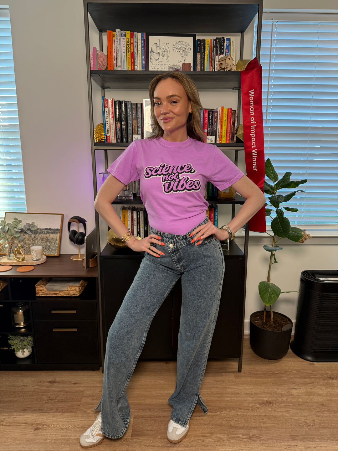 woman wearing purple shirt with "science, not vibes" on it; in an office