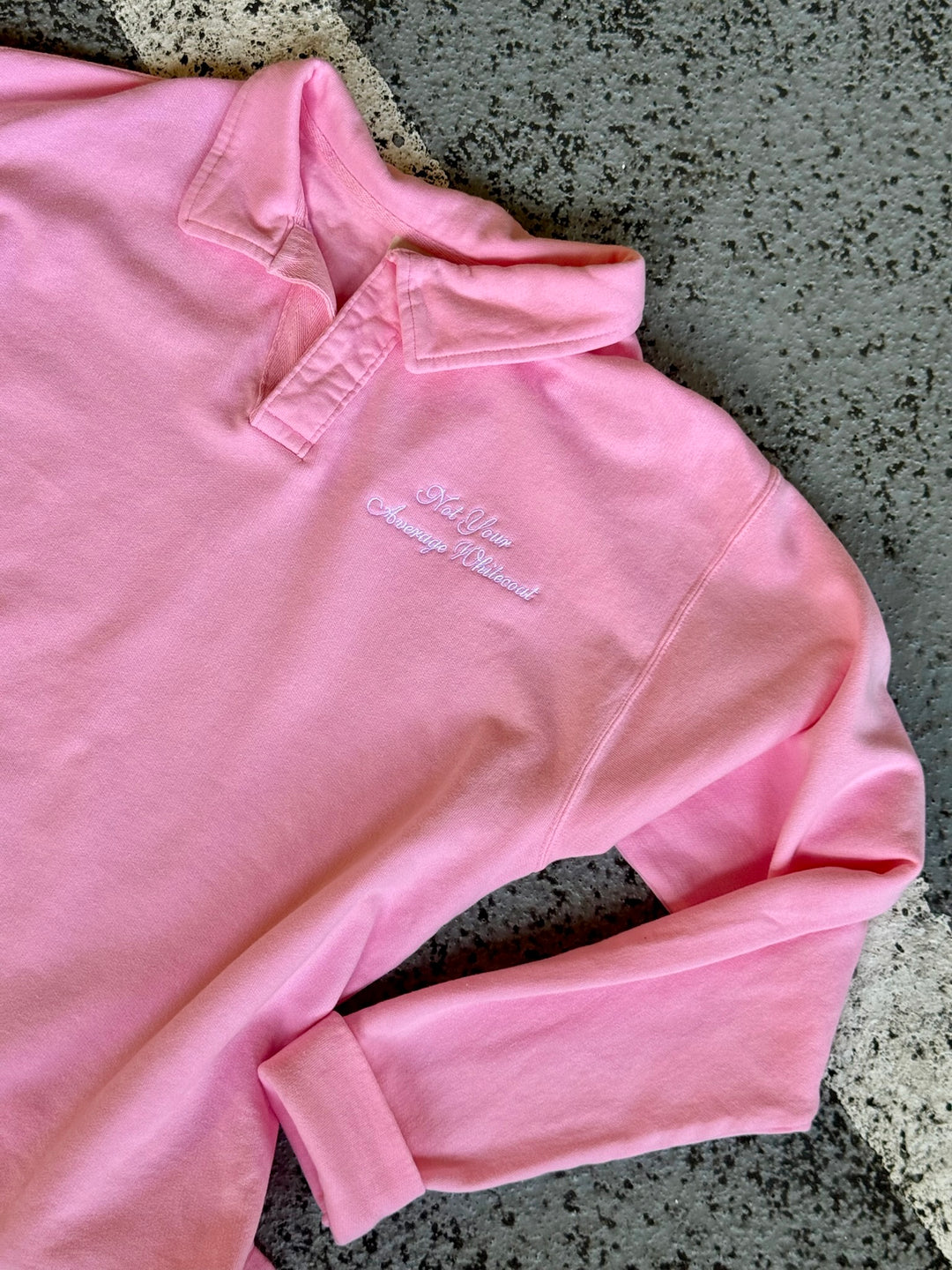Flat lay of Not Your Average Whitecoat Pink Polo Collar Sweatshirt lying on a textured surface