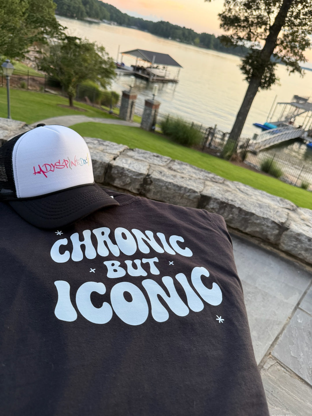 Ladyspinedoc trucker hat and T-shirt with 'Chronic But Iconic' text and cap on a lakeside background