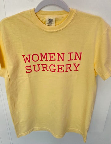 Yellow t-shirt with 'WOMEN IN SURGERY' text in pink on a hanger against a white background