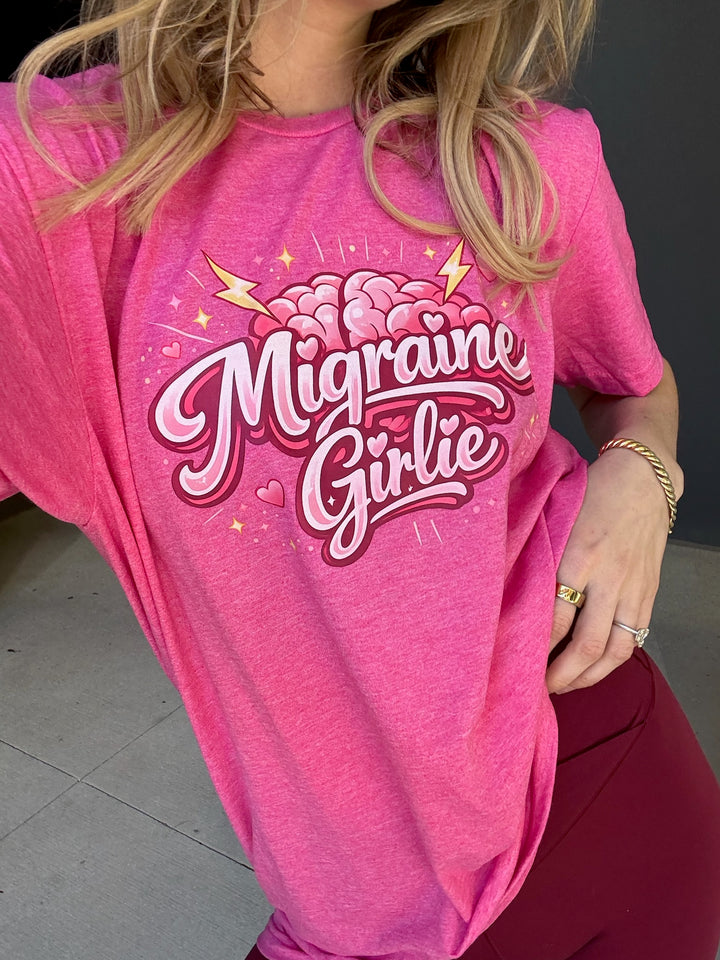 Person wearing a pink t-shirt with 'Migraine Girlie' design.