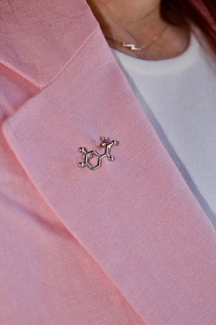 Ladyspinedoc wearing pink blazer with a silver Dr. Beachgem Noradrenaline Molecule Lapel Pin