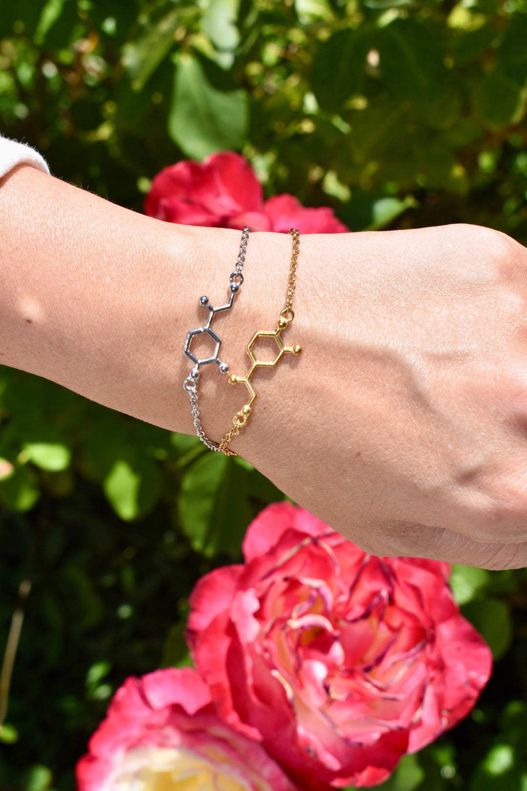 Two Dr. Beachgem noradrenaline molecule bracelets  on a wrist against a floral background