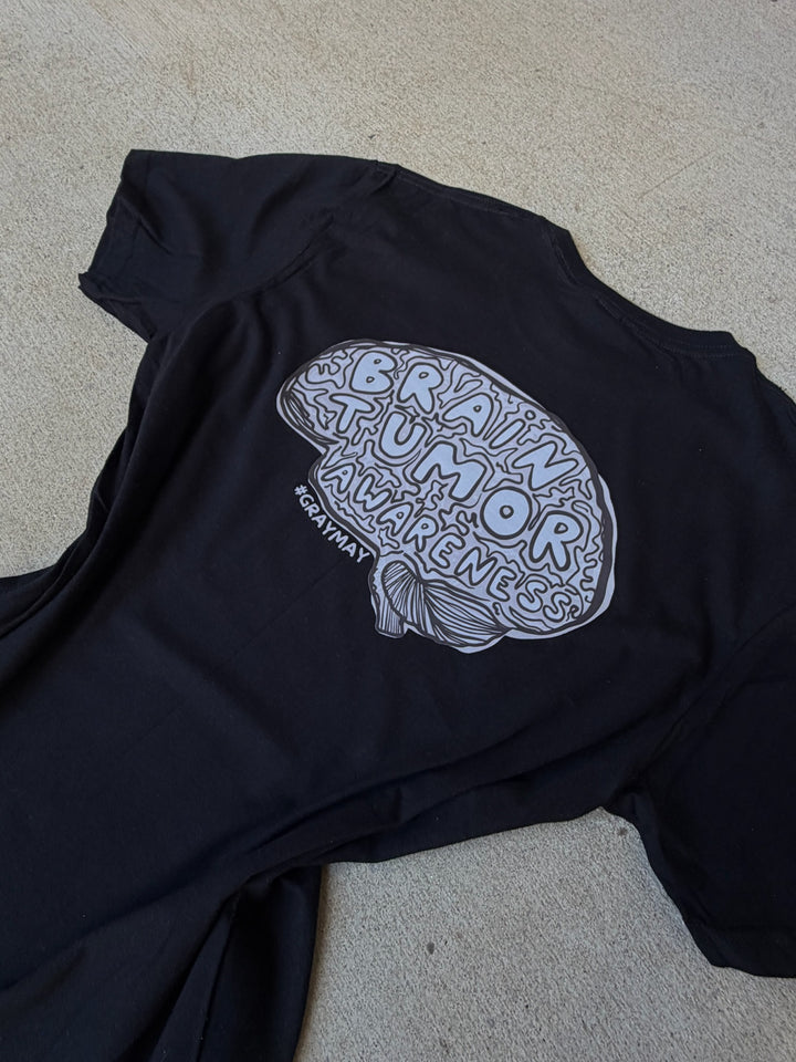 Black t-shirt with white brain tumor awareness design on a beige surface