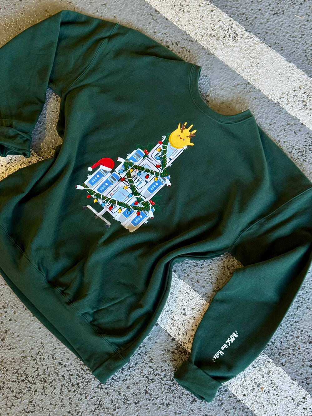 Green ROSC the Halls | IV Pump Christmas sweatshirt with a festive design on a concrete surface